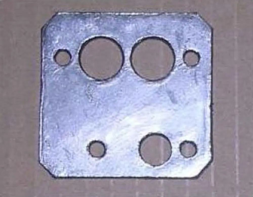 Metallplatte mit mehreren Löchern in unterschiedlichen Durchmessern, vermutlich Teil einer Dichtung oder Dichtungsanwendung. Marke: Remeha.